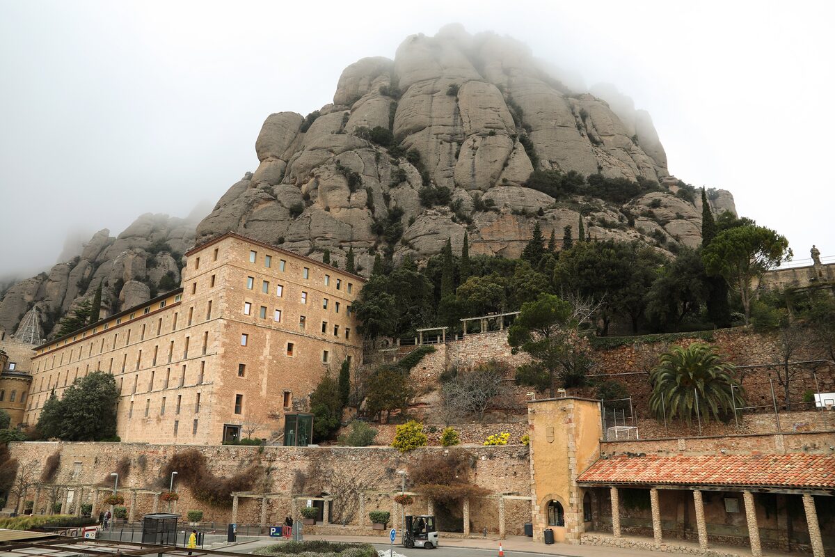 Montserrat monastery buildings below the rock walls, under low cloud