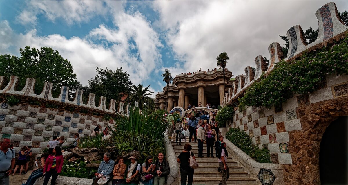 Mosaic staircase and stone pavilions at the entrance of Park Güell, with visitors