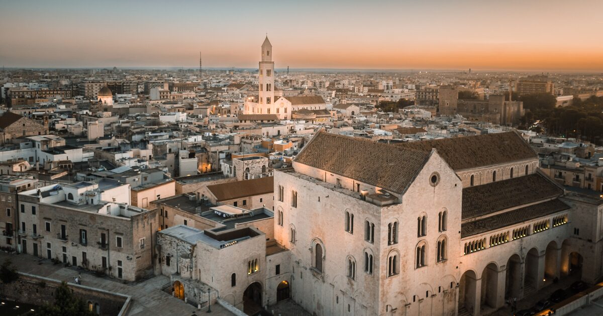 Aerial view of Bari at sunset, with the Basilica of San Nicola in the foreground and the old town rooftops and a bell tower behind