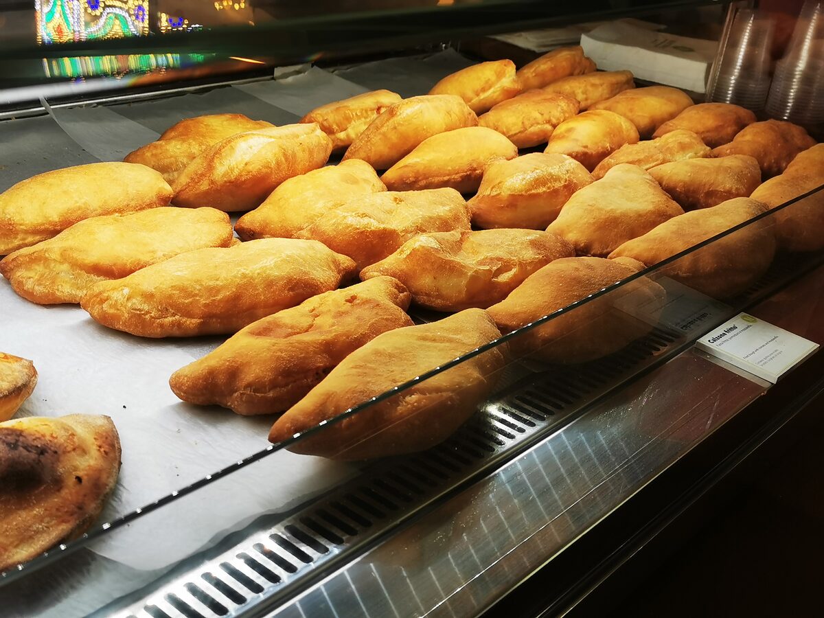 Golden fried panzerotti piled behind the glass of a takeaway counter