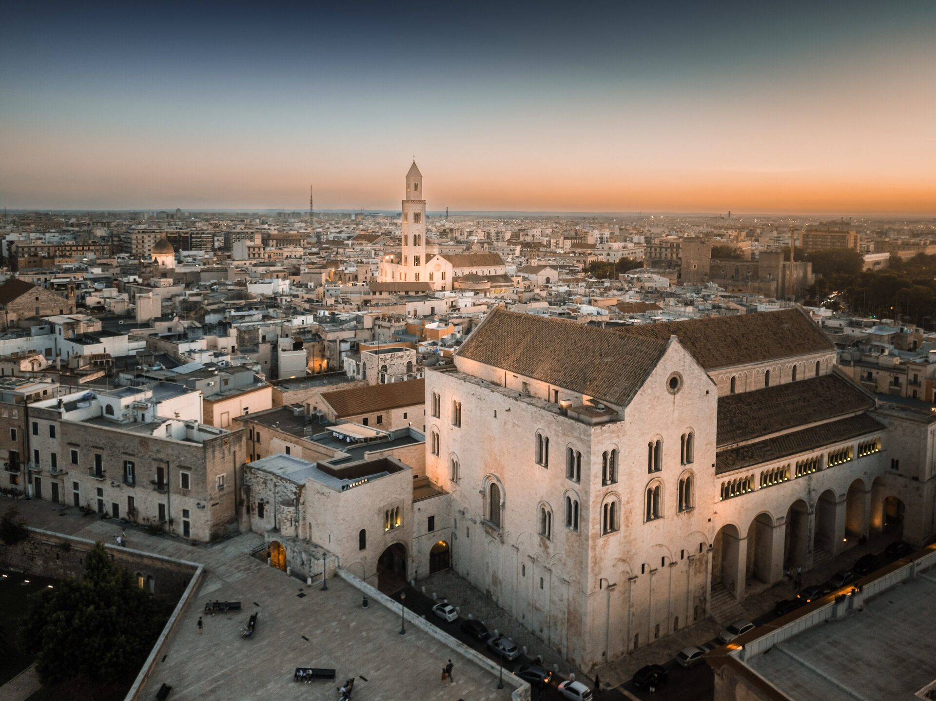 Aerial view of Bari at sunset, with the Basilica of San Nicola in the foreground and the old town rooftops and a bell tower behind
