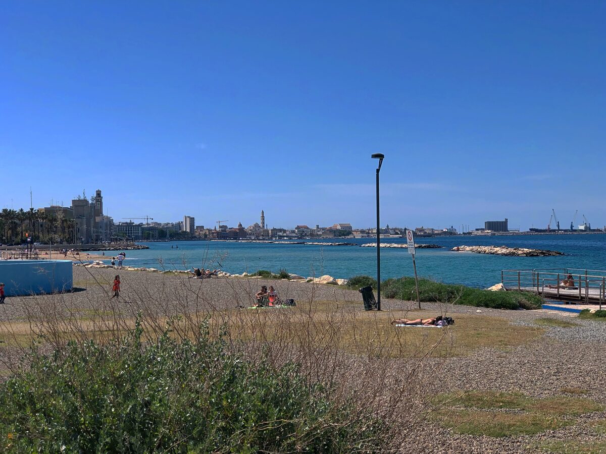 The pebbly city beach at Pane e Pomodoro, with the Bari shoreline and the harbour across the bay