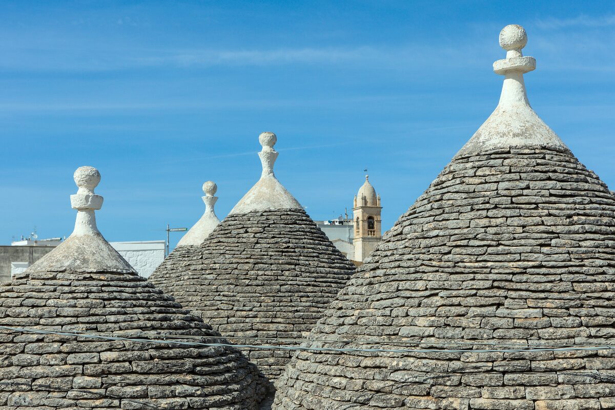 Stone cone roofs of the trulli in the Rione Monti of Alberobello, against a blue sky