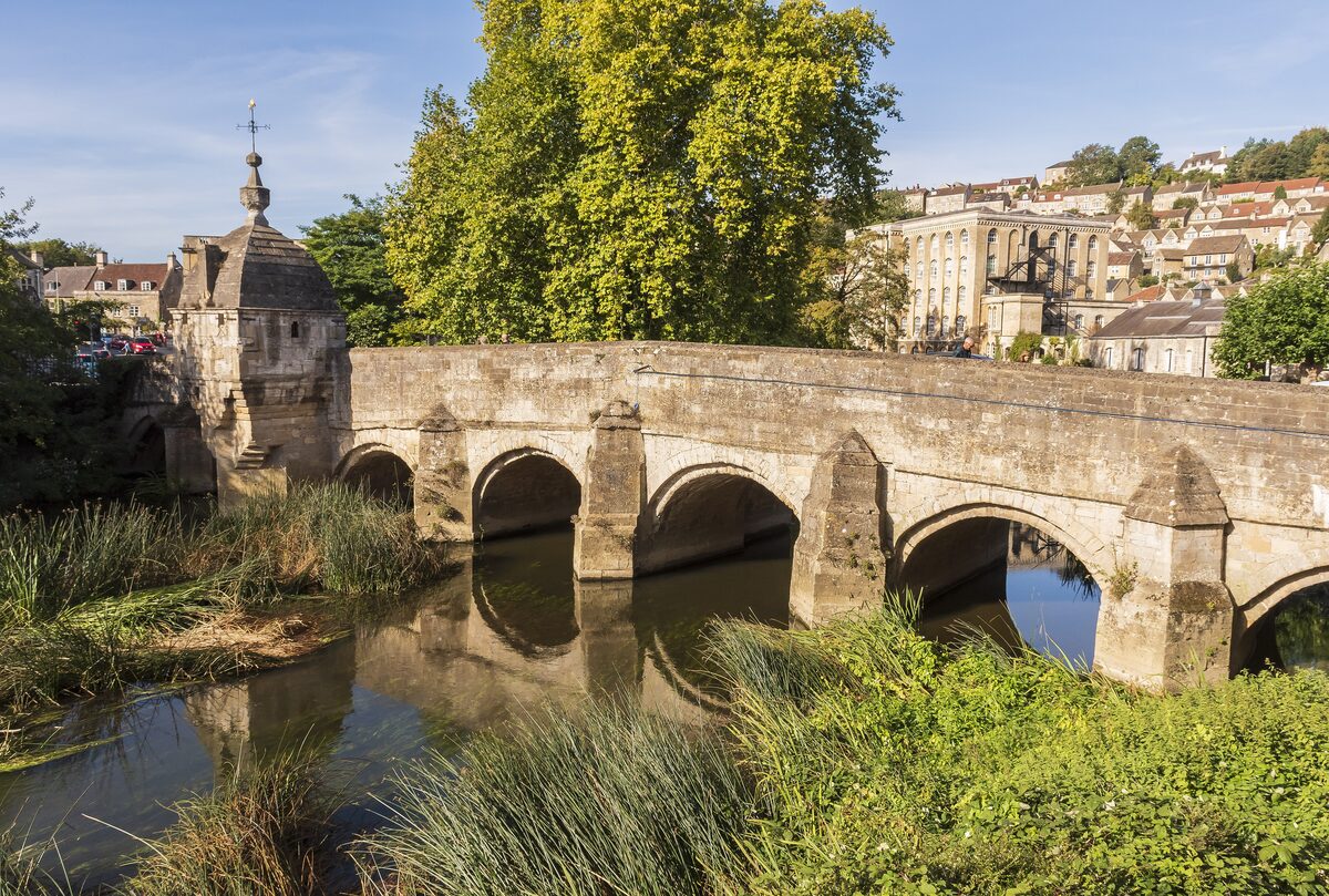 The medieval Town Bridge over the River Avon at Bradford-on-Avon, with its little domed lock-up and stone houses on the hill