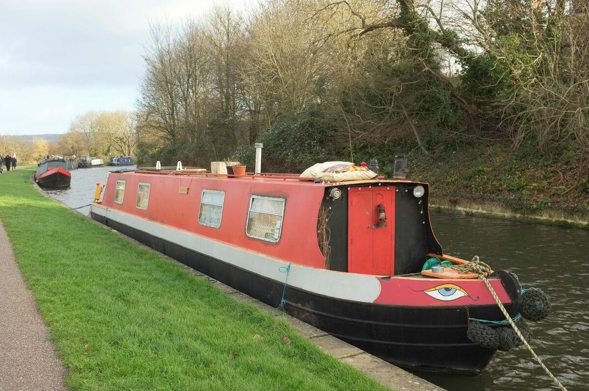 Narrowboats moored along the Kennet and Avon Canal near Bath, with a towpath and trees on the bank