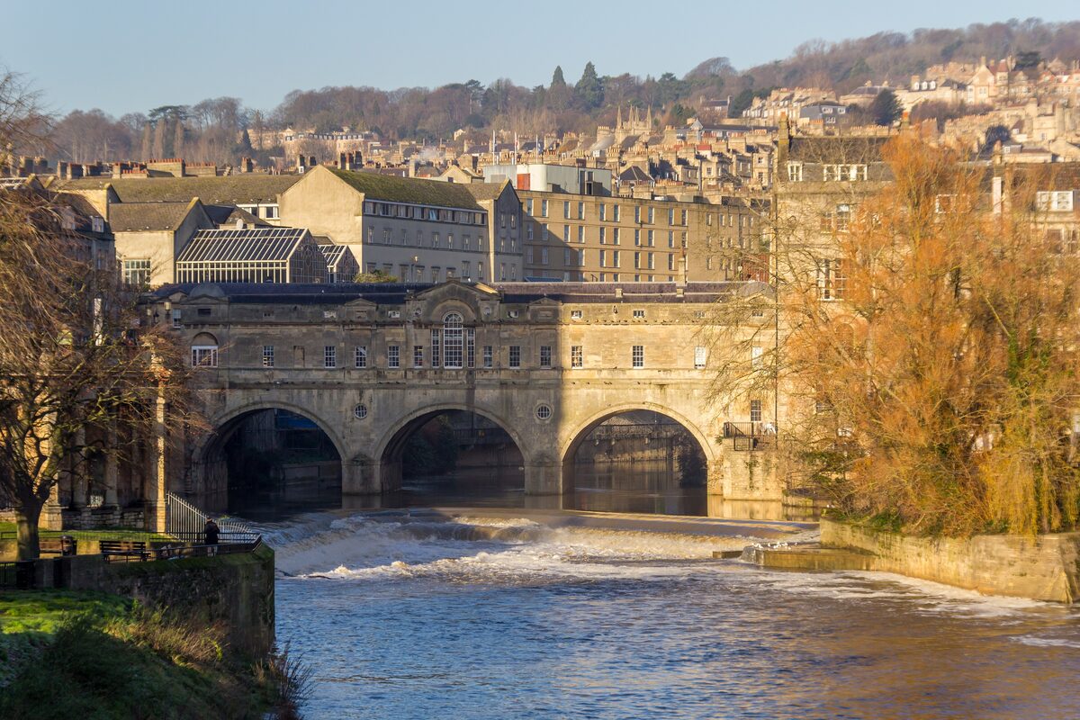 Pulteney Bridge in Bath with its three arches and little shops above them, and the curved steps of the weir in front
