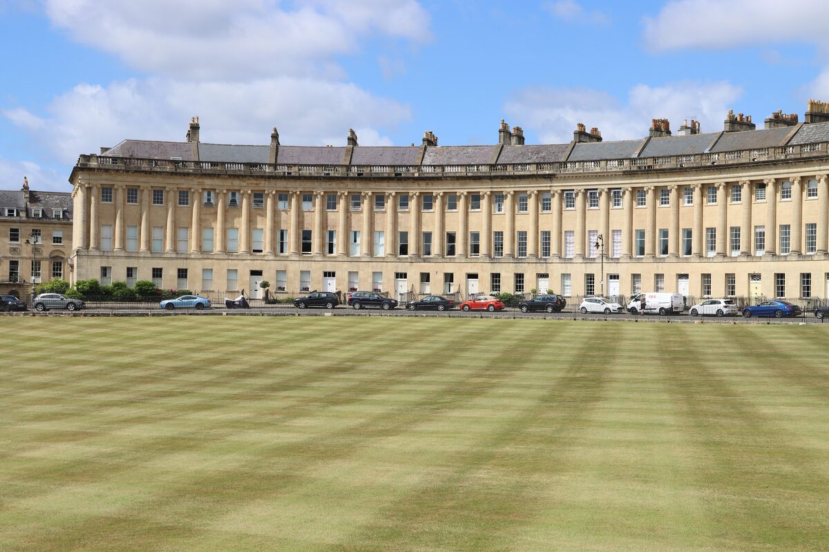The long curve of the Royal Crescent in Bath, its row of honey-colored stone houses behind a wide green lawn