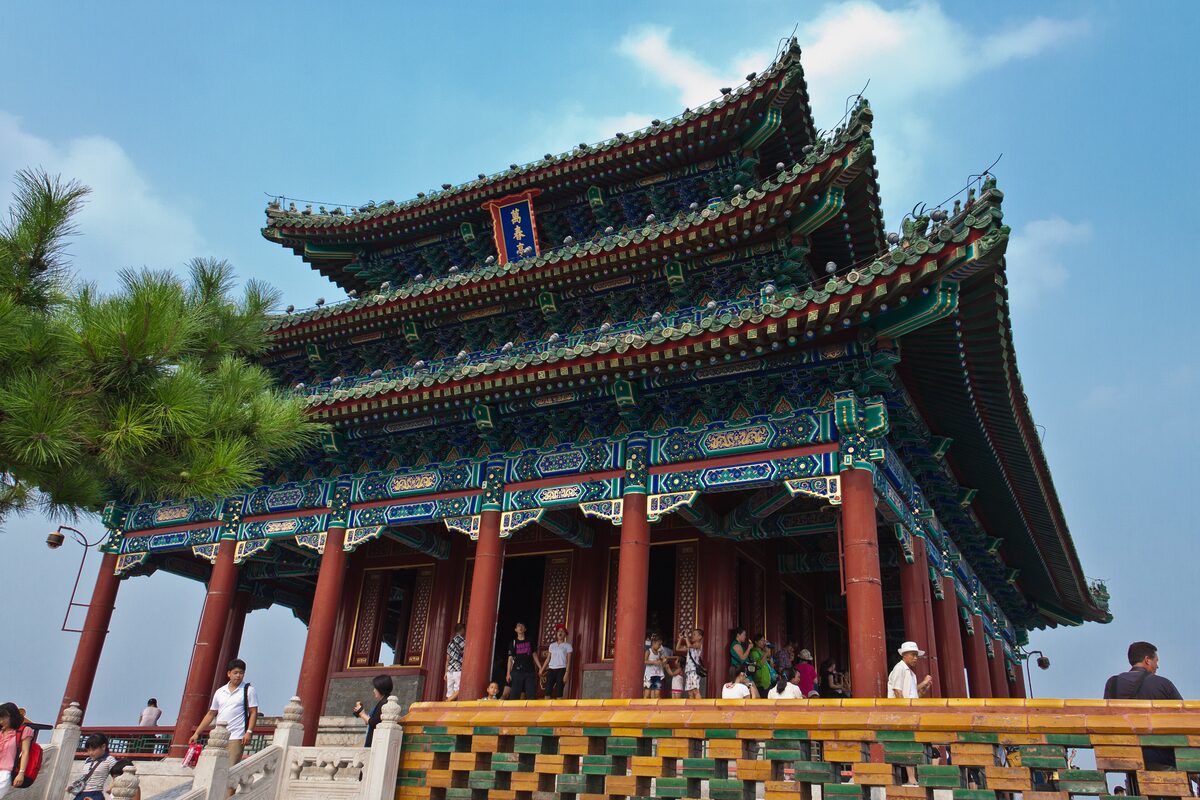 The three-roofed pavilion on top of Jingshan hill, with red columns, blue and green painted eaves and visitors on the terrace below