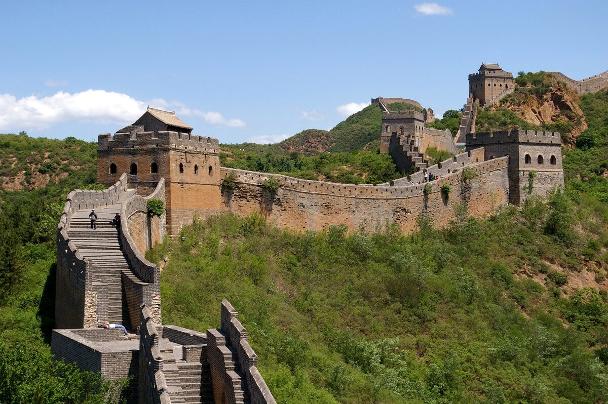 Stone watchtowers and wall at Jinshanling climbing a green ridge under a blue sky