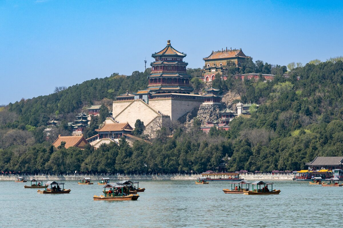 Longevity Hill and its temple buildings rising above Kunming Lake, with small tour boats on the water