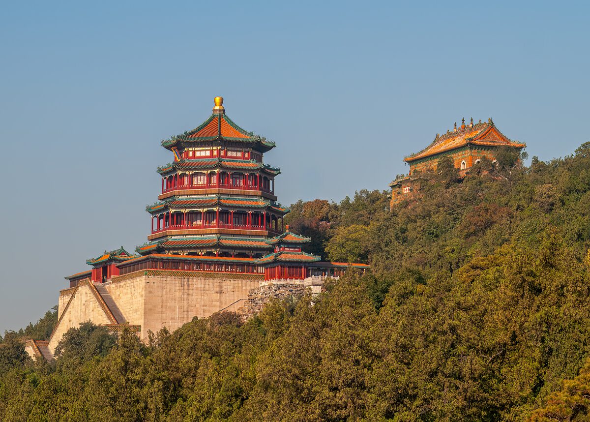 The red and gold Tower of Buddhist Incense on its stone terrace on the forested Longevity Hill
