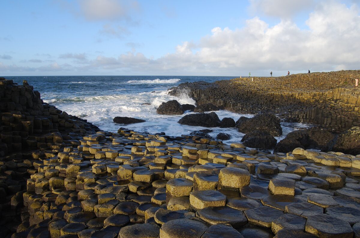 The hexagonal basalt columns of the Giant's Causeway stepping down into the sea under a blue sky