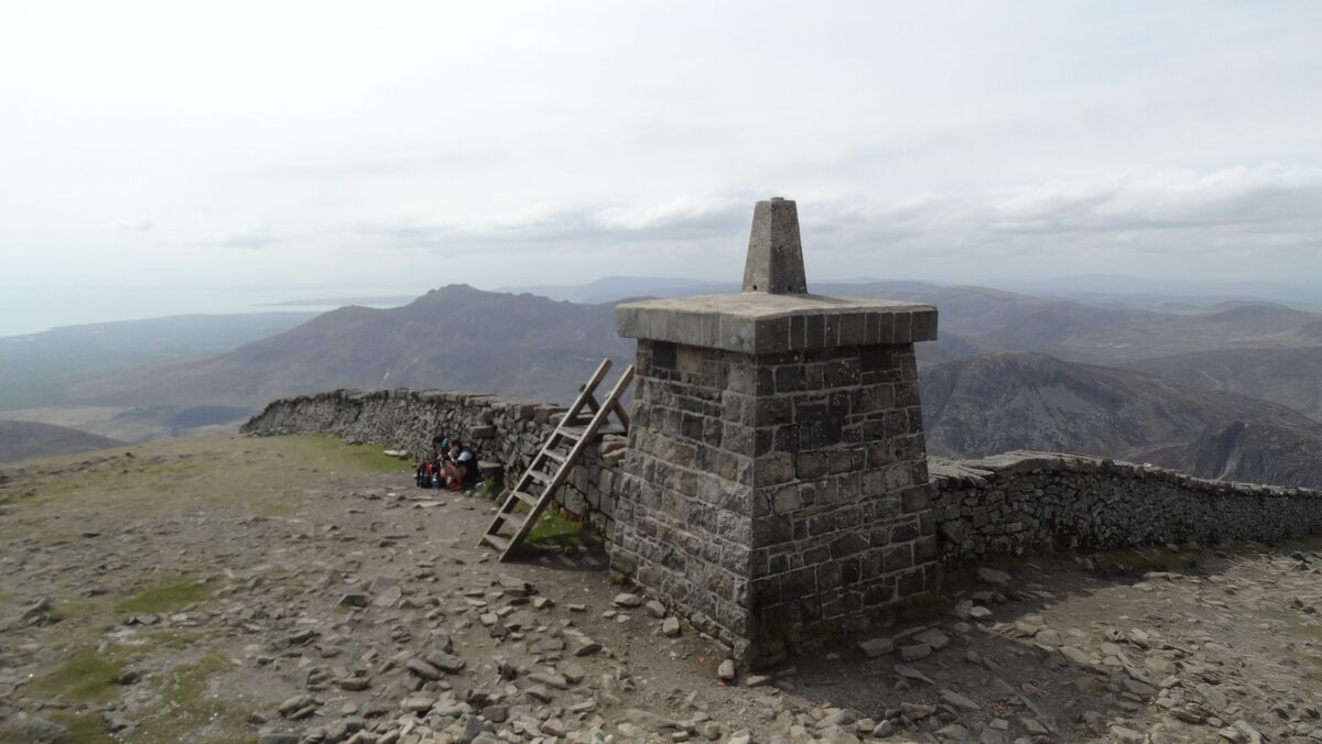 The stone summit cairn of Slieve Donard and the Mourne Wall running across the bare hills of the Mournes