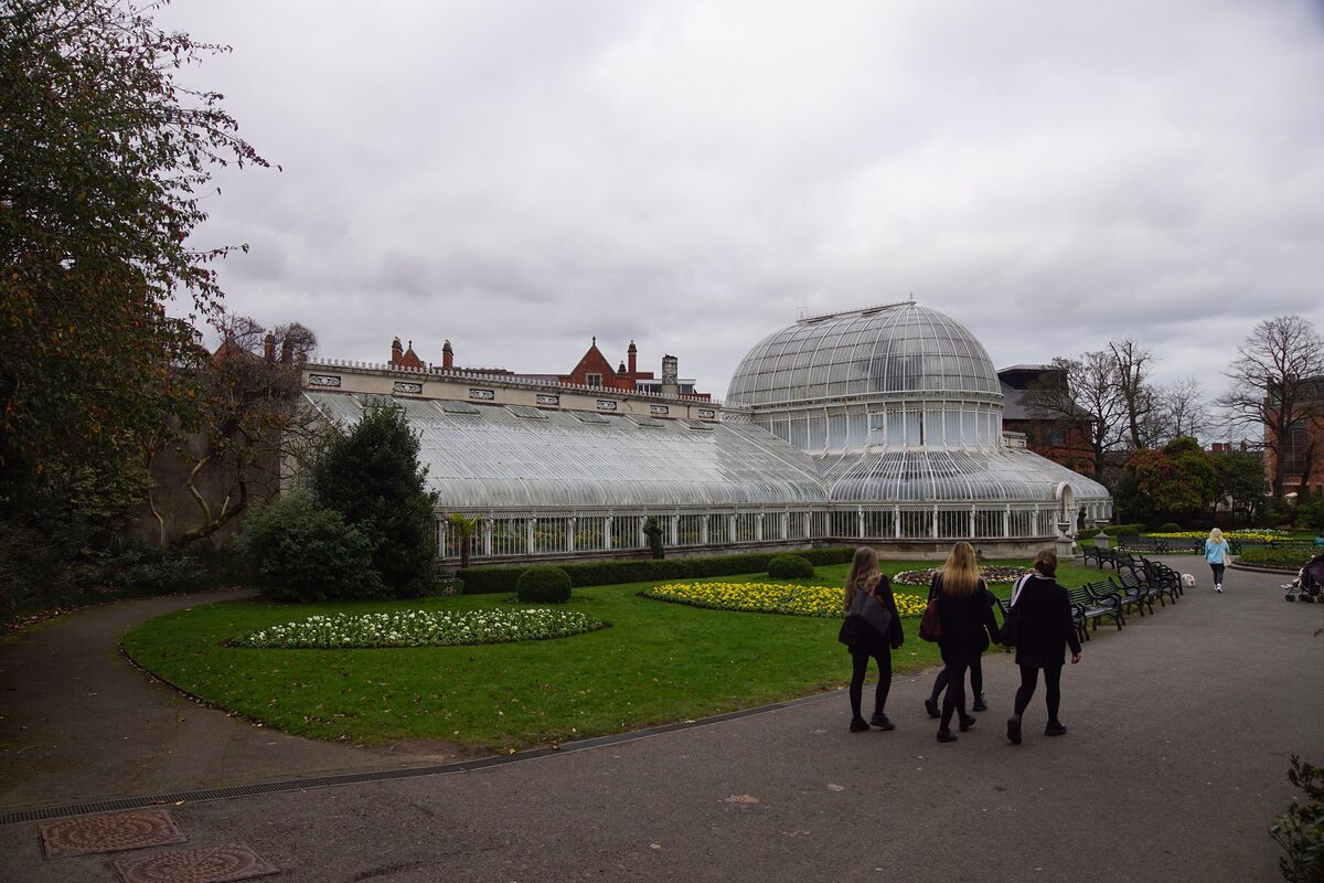 The curved white glass and iron Palm House in Belfast's Botanic Gardens, with flower beds in front