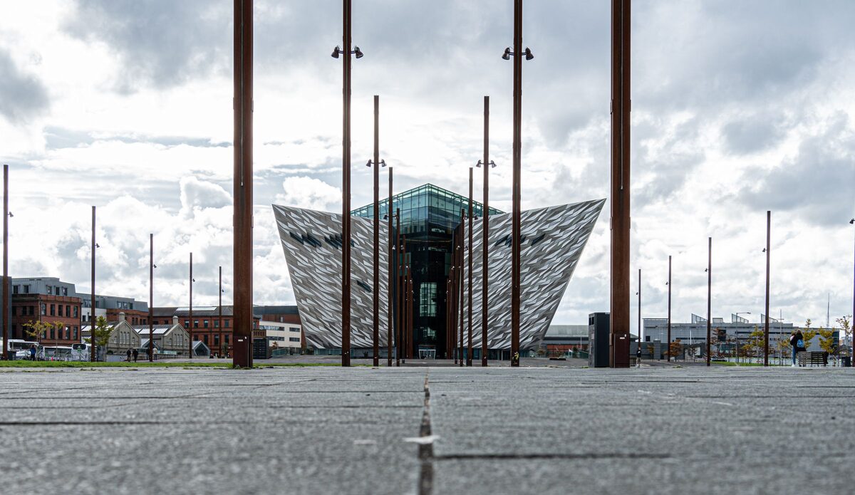 The angular silver Titanic Belfast building at the end of the old slipways, between tall steel posts