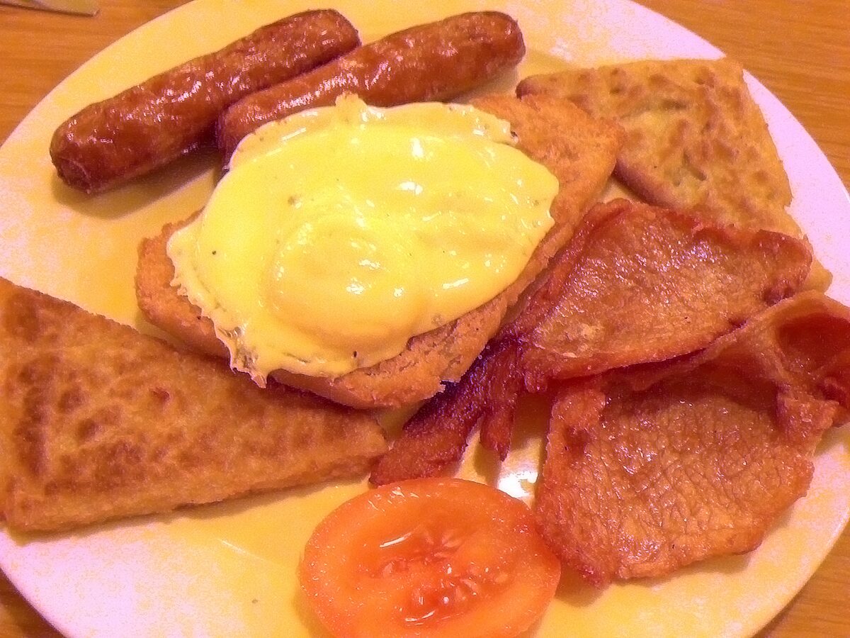 An Ulster fry with sausages, bacon, a fried egg, tomato and triangles of fried soda bread and potato bread