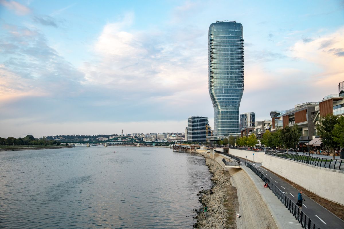 The twisting glass Kula Belgrade tower next to the Sava promenade at dusk