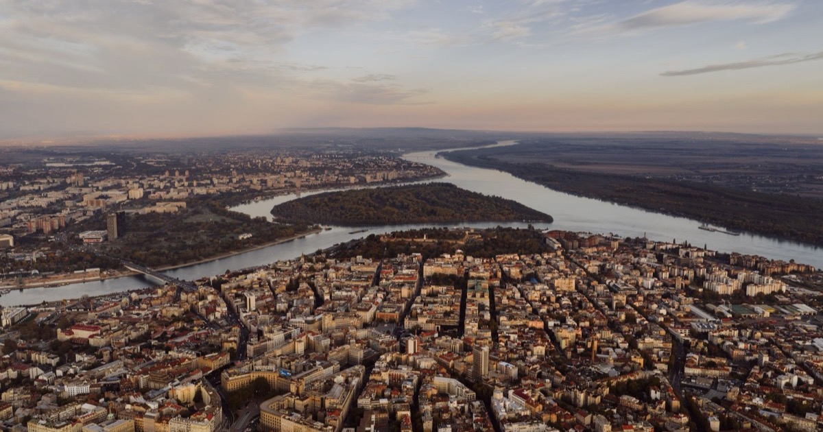 Aerial view of Belgrade at dusk, with the old town and Kalemegdan in front and Great War Island where the Sava meets the Danube