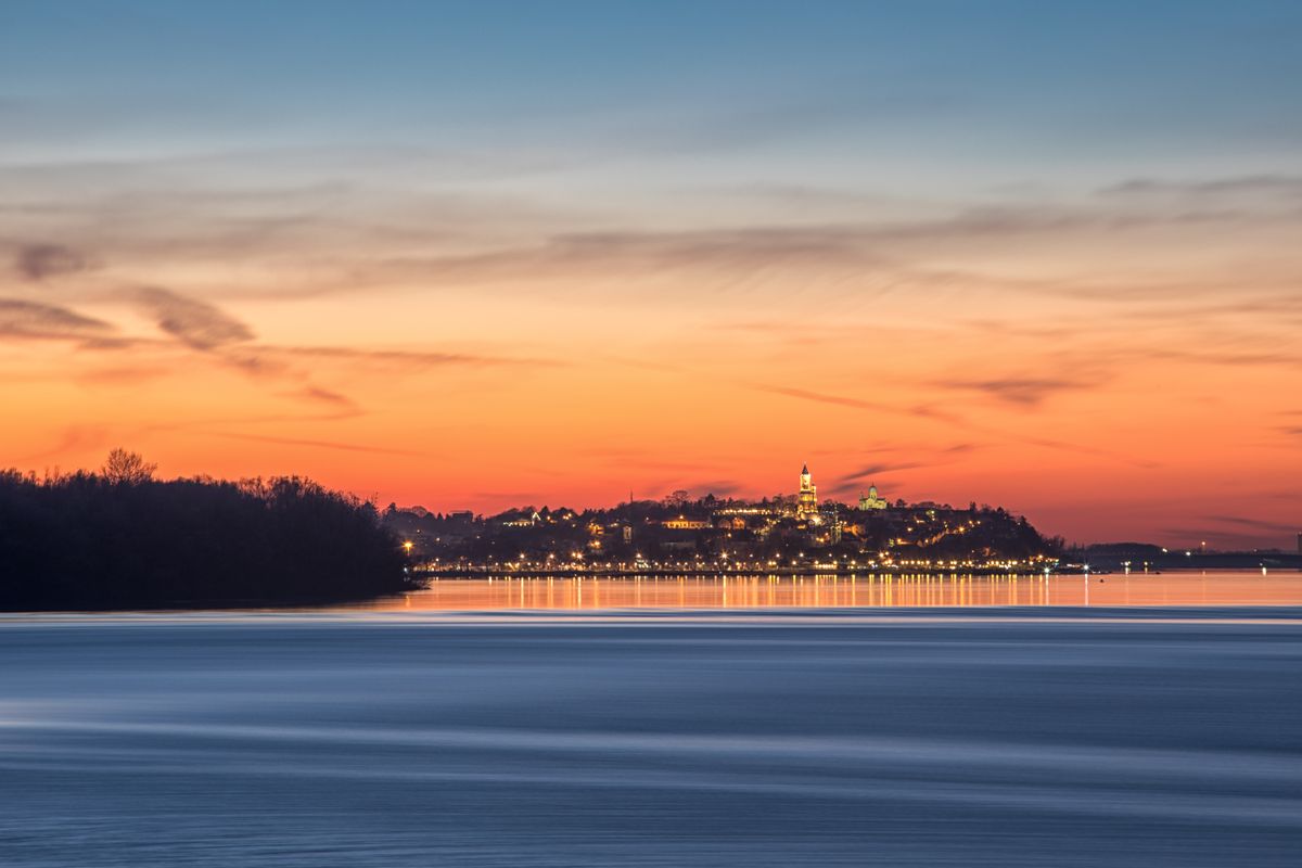 The lights of Zemun and Gardoš Tower across the Danube at sunset