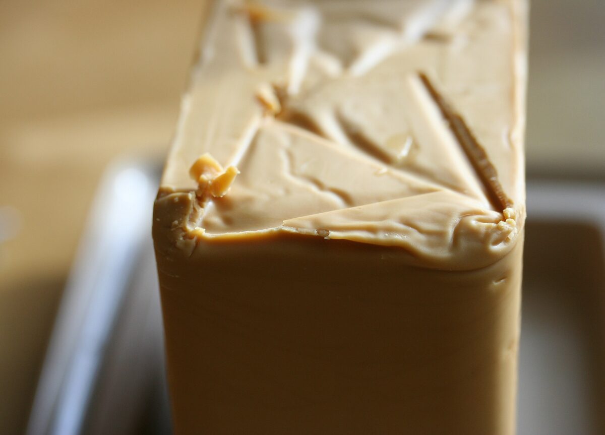 A block of brown whey cheese with thin slices shaved off its top