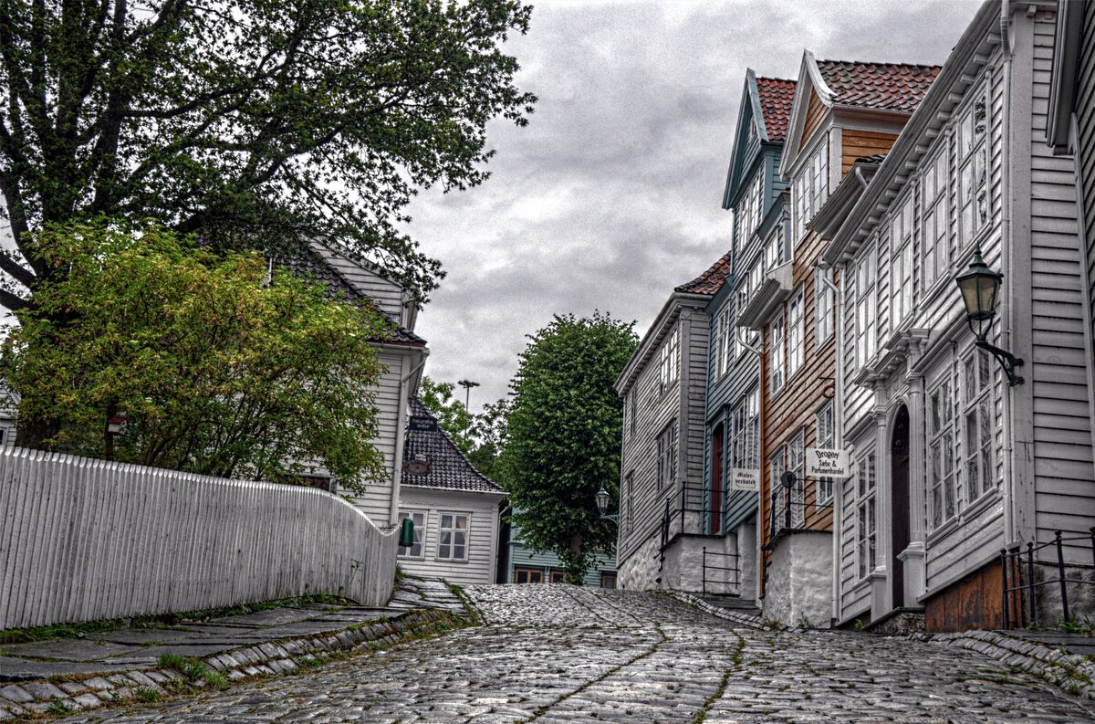 A cobbled street of old white and grey wooden houses with a street lamp at Gamle Bergen museum
