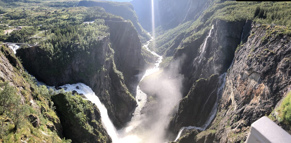 The Vøringsfossen waterfall plunging into a deep green canyon with spray rising into the sunlight
