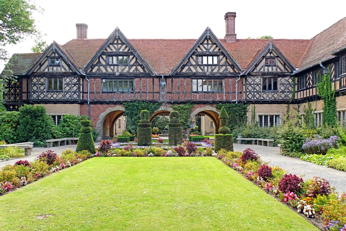 The half-timbered Tudor-style courtyard of Cecilienhof Palace, with clipped hedges and flower beds in front