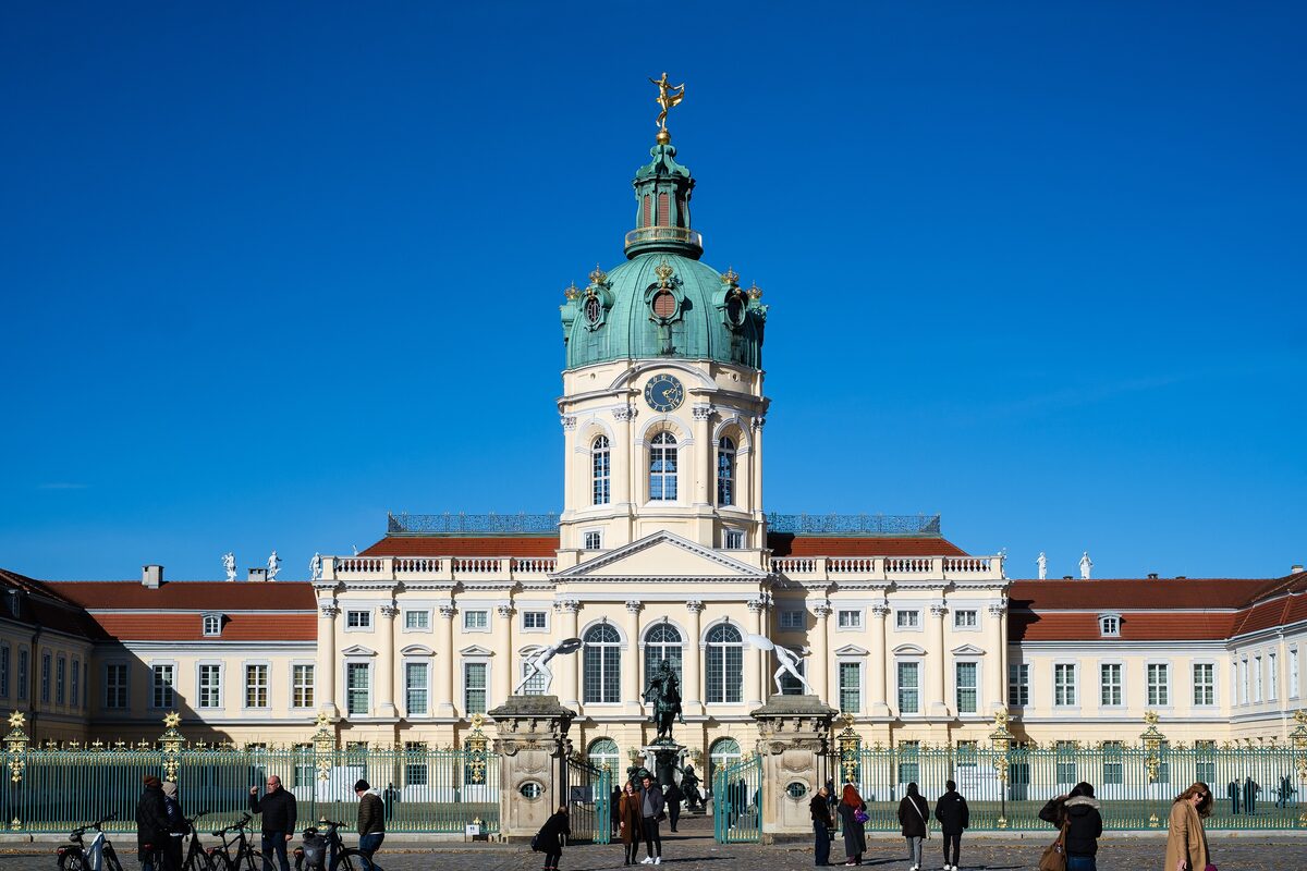 The domed central block of Charlottenburg Palace behind its gilded fence, under a deep blue sky