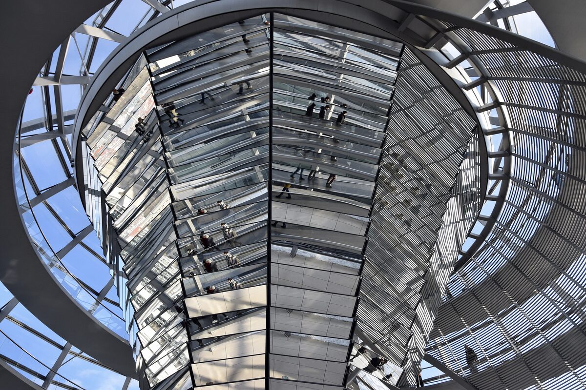 Looking up into the mirrored cone inside the glass dome of the Reichstag, with visitors on the spiral ramp reflected in it