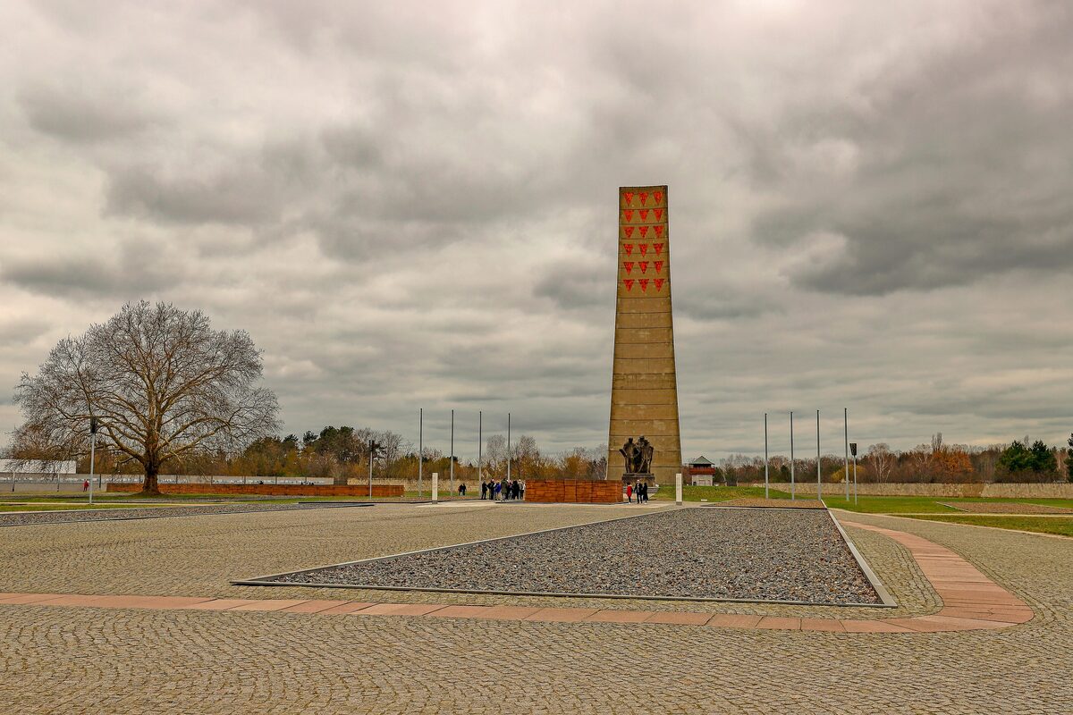 The Liberation Obelisk and the paved parade ground at the Sachsenhausen Memorial, under a heavy grey sky