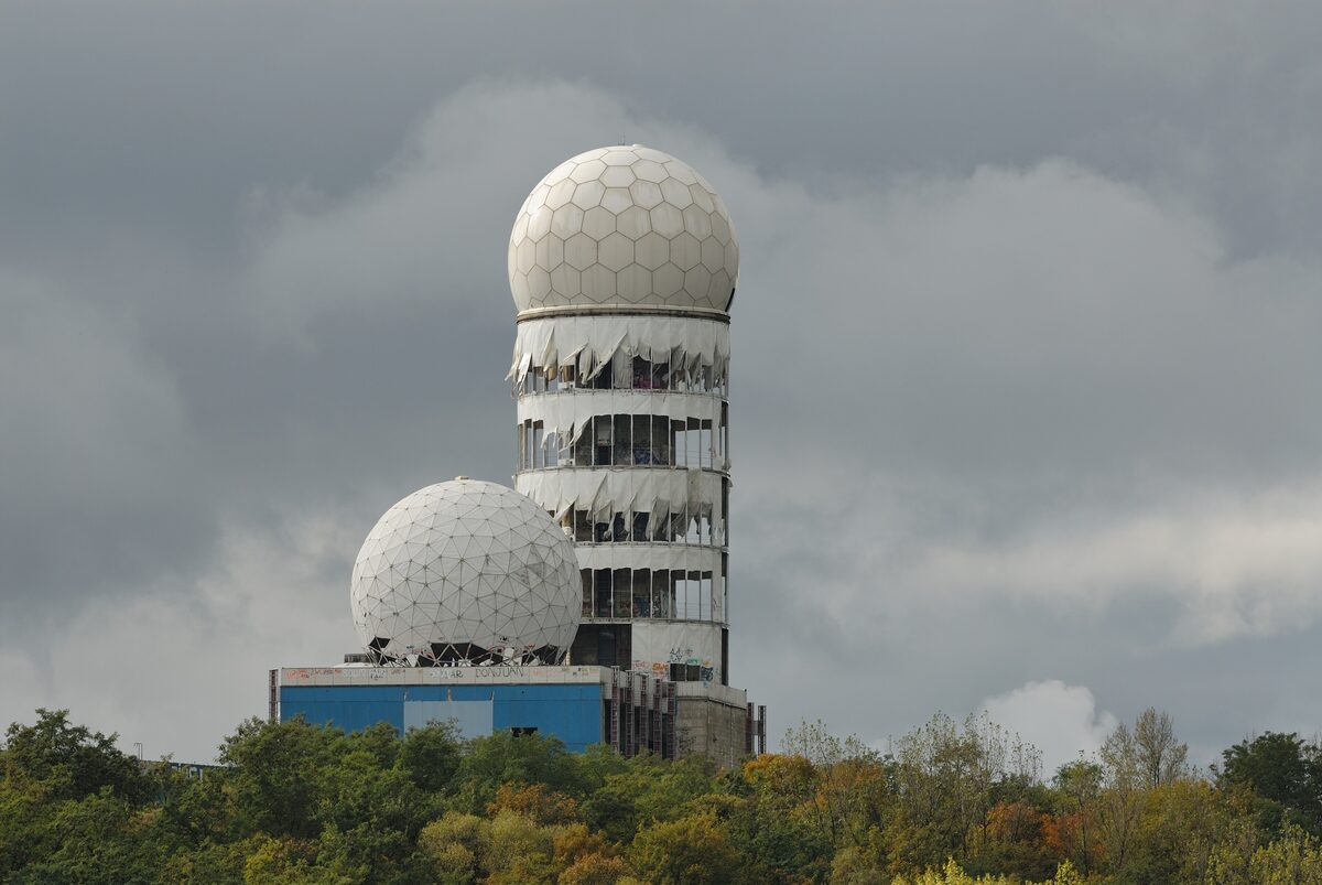 The white domes and ruined tower of the former listening station on Teufelsberg above autumn treetops