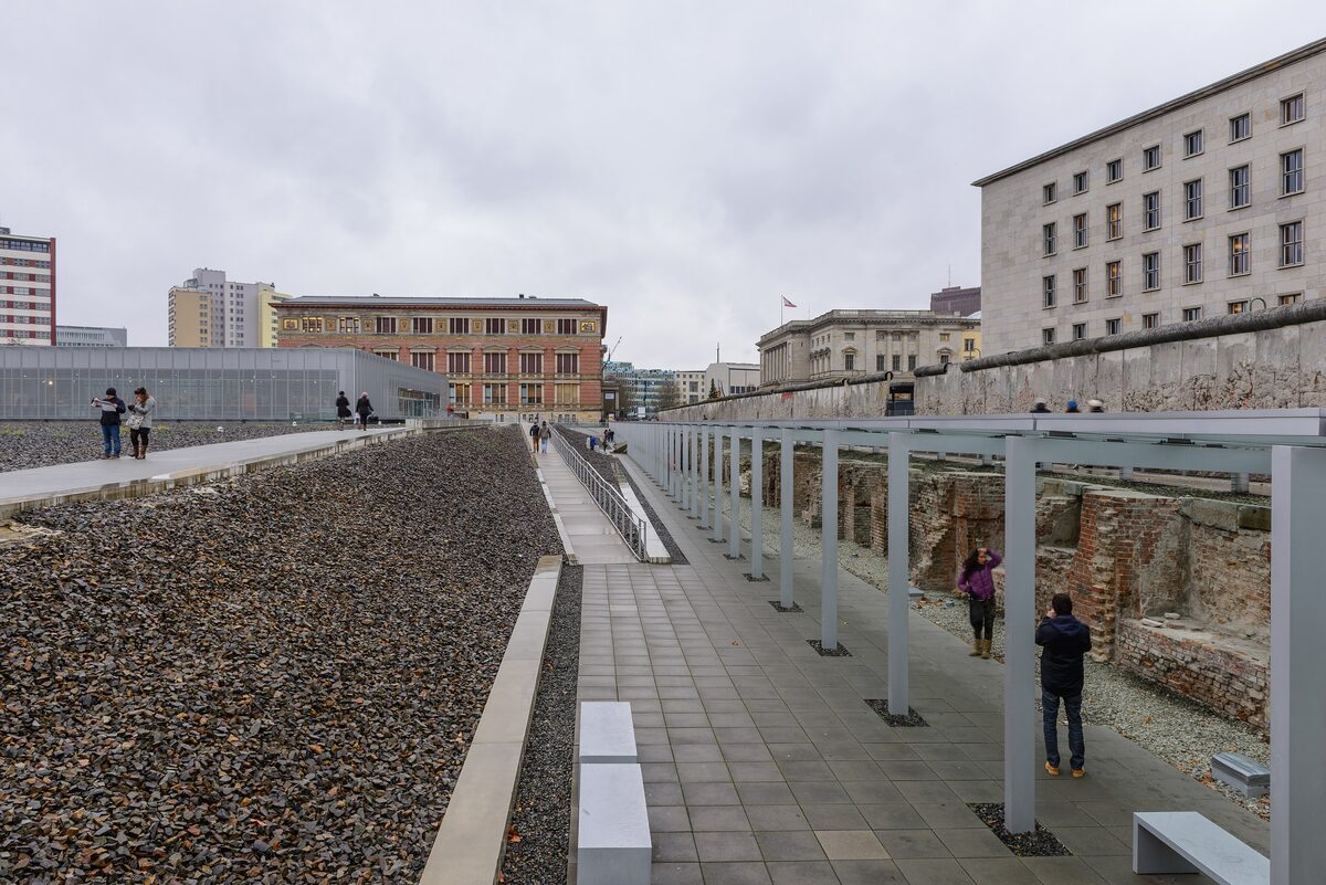 The Topography of Terror site, with a gravel strip, excavated cellar walls, a stretch of the Berlin Wall and a former Nazi ministry building behind