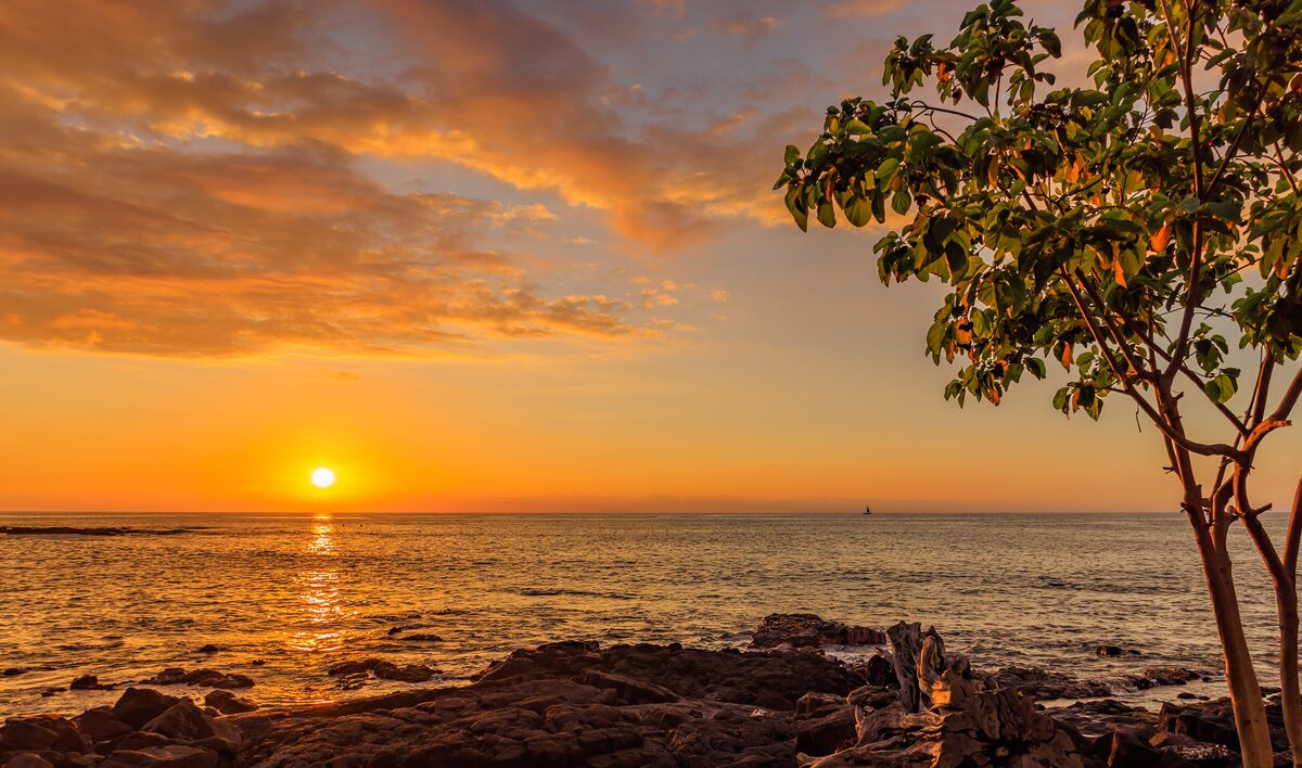 Orange sunset over lava rocks and the sea at Kailua-Kona