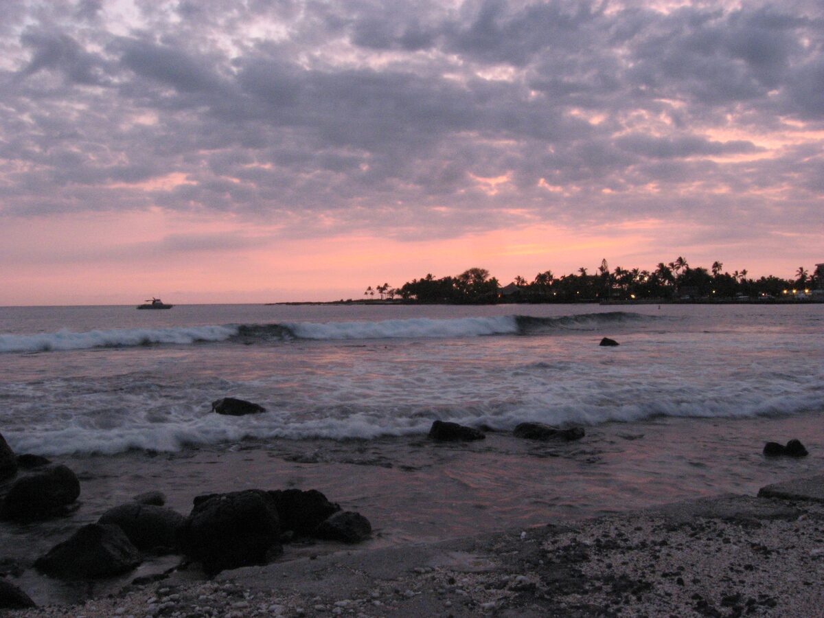 Pink dusk sky over rocks and surf on the Kailua-Kona shore