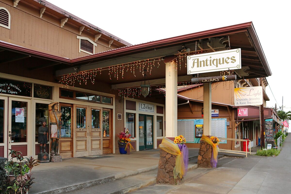 Wooden storefronts with an Antiques sign on Hāwī's main street