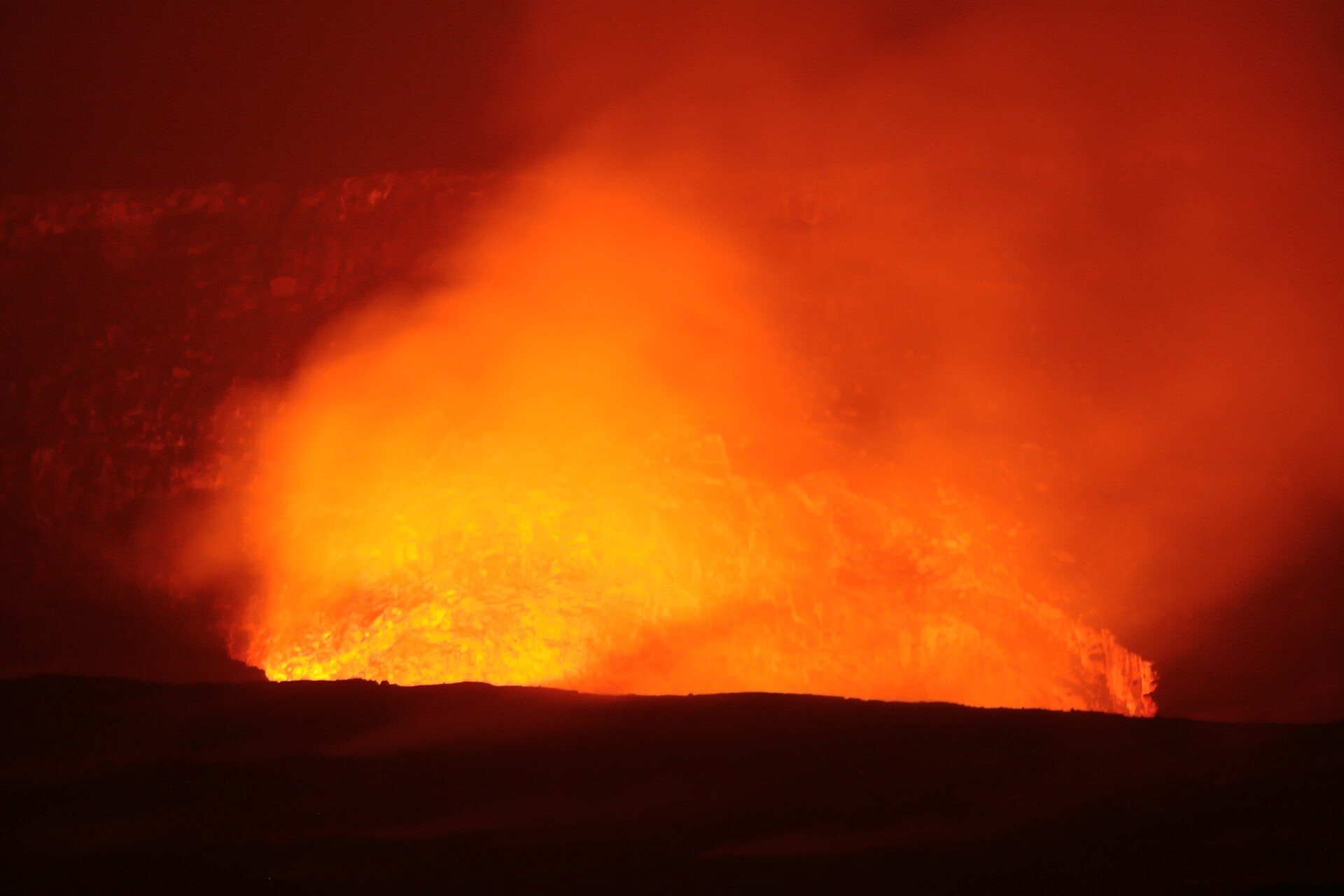 Orange lava glow lighting the Halemaʻumaʻu crater under a night sky