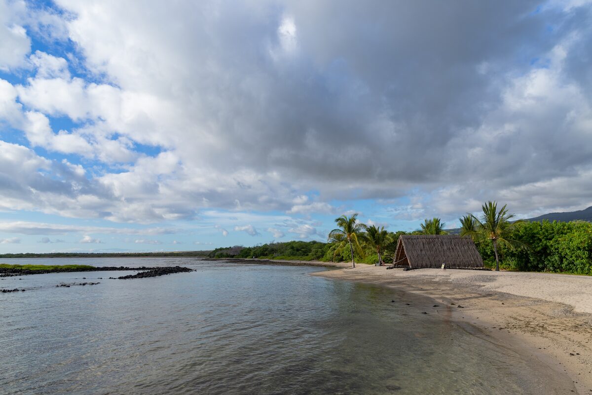 Calm lagoon, sandy shore and a thatched hale at Kaloko