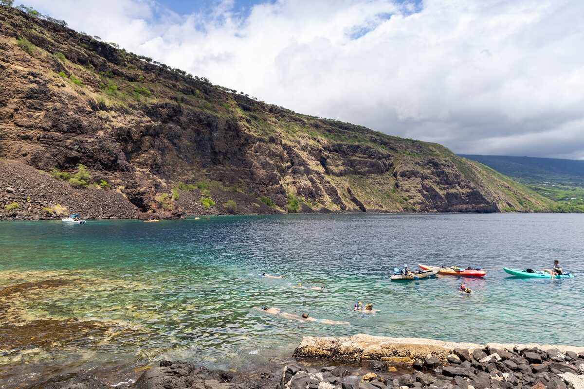 Swimmers and kayaks in the clear water of Kealakekua Bay