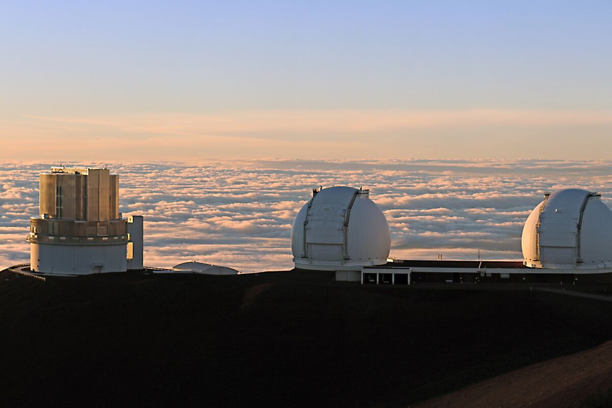 Two white observatory domes above the clouds on Mauna Kea