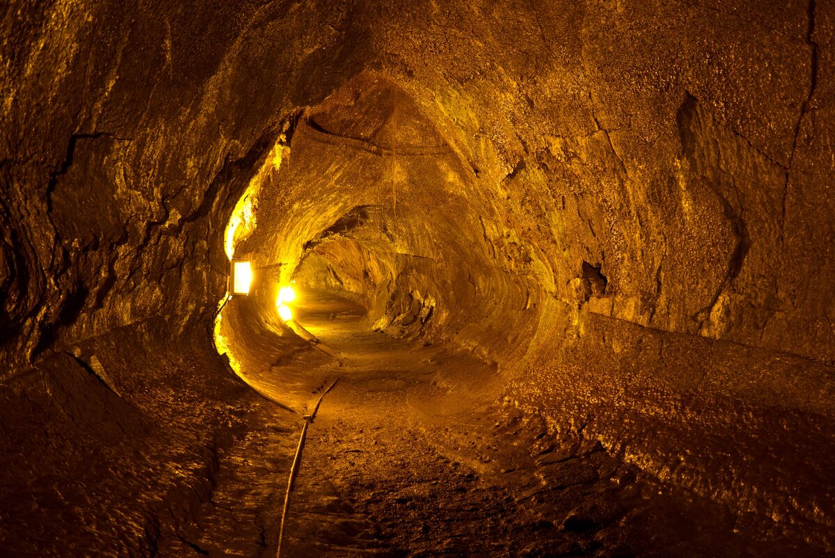 Lit lava tube tunnel with brown rock walls at Nāhuku