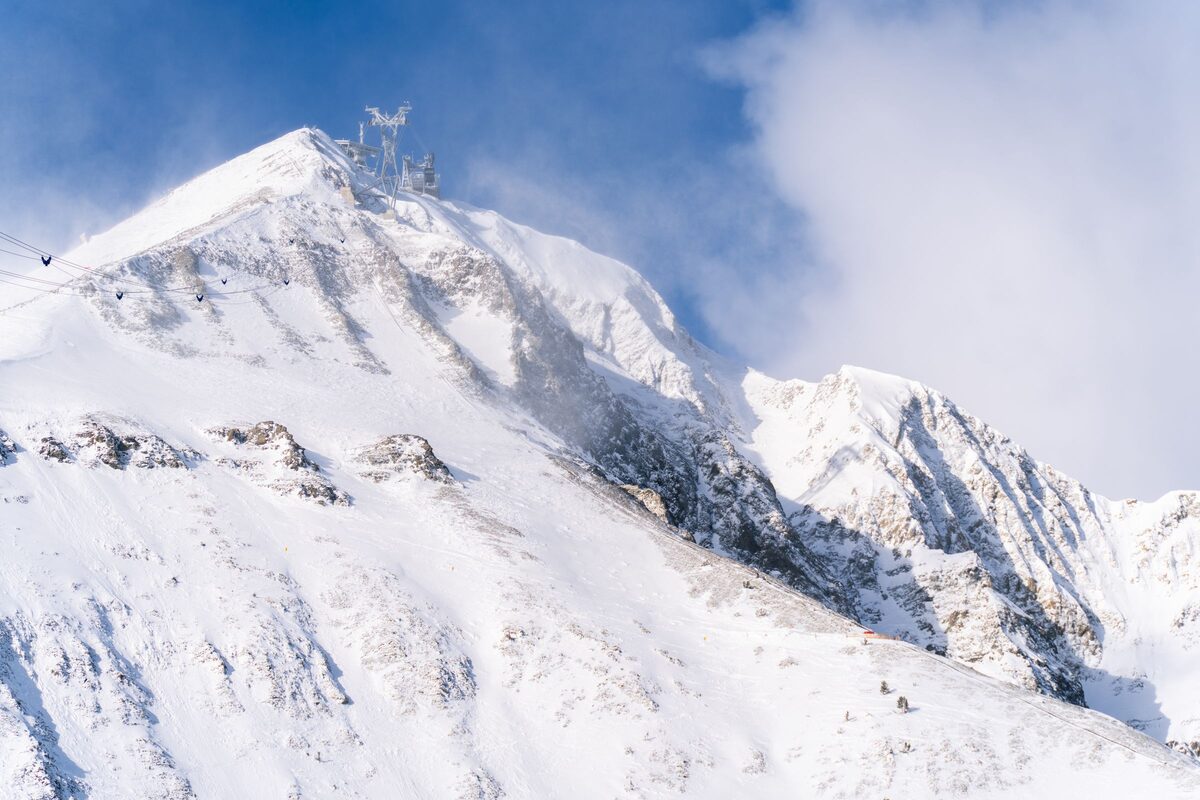 The steep, snow-plastered summit of Lone Peak with the tram line and tower on the ridge above rocky gullies