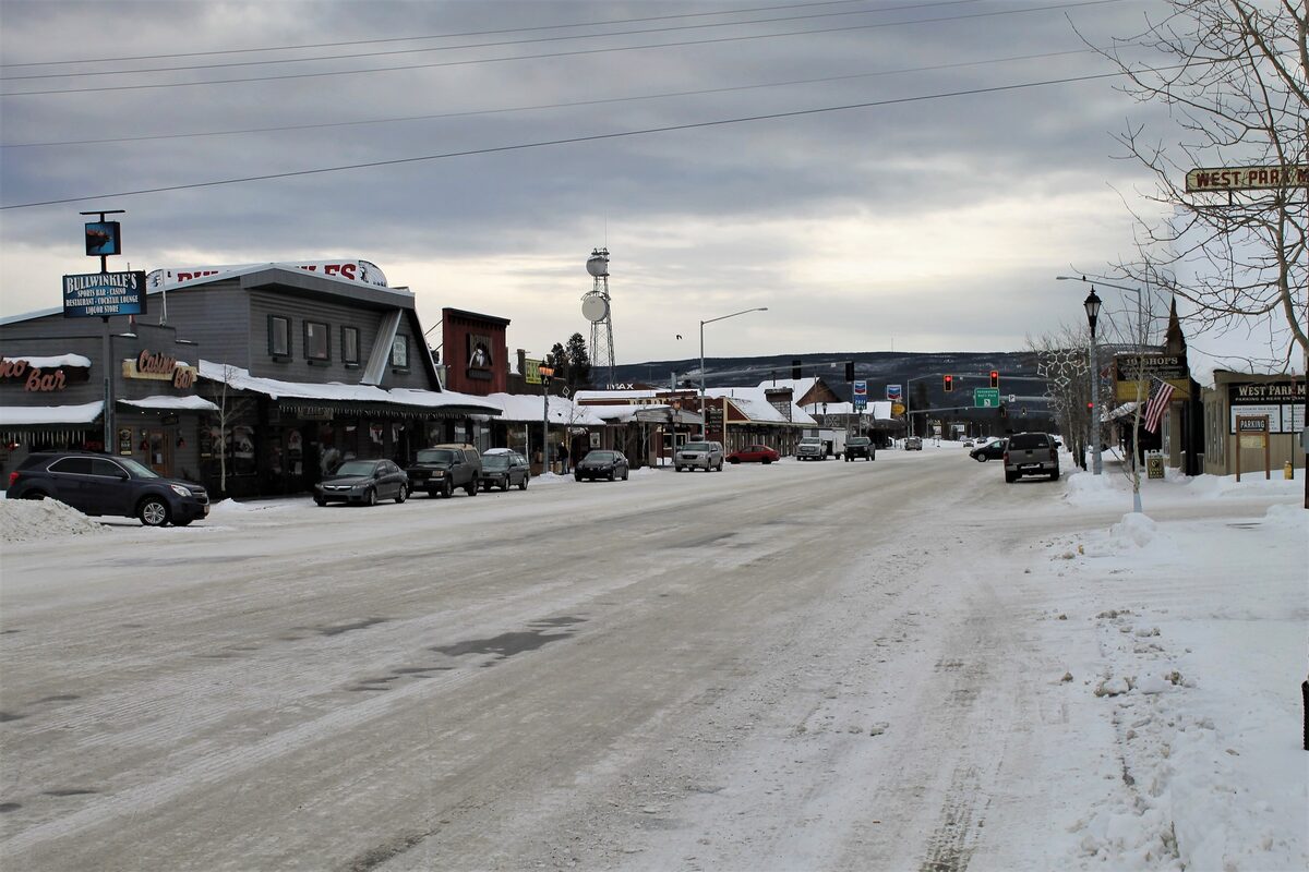 The main road through West Yellowstone in January, lined with bars and shops under a thin layer of snow and ice, a grey sky above