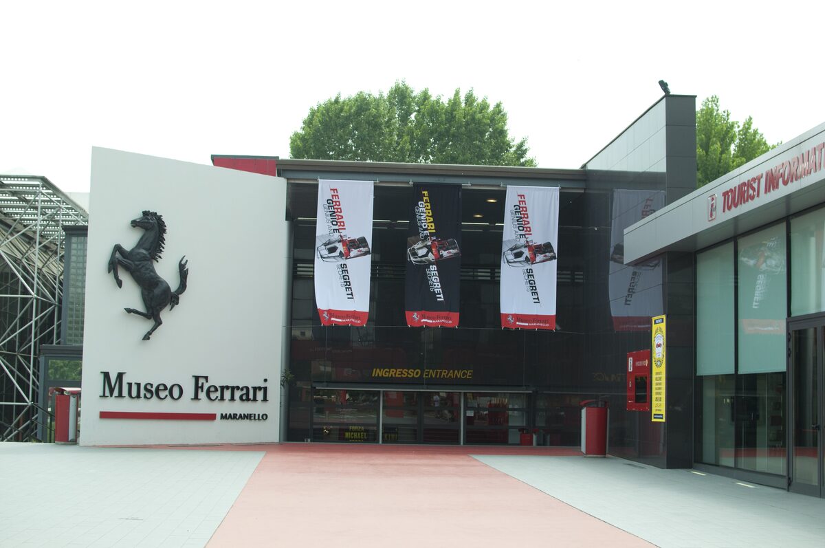 The entrance of the Museo Ferrari in Maranello, with the prancing horse logo on the white wall
