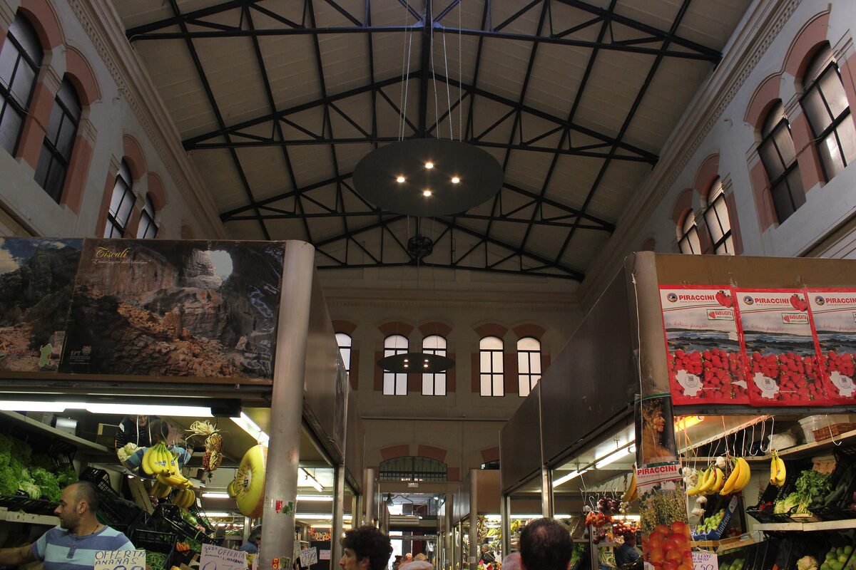 Inside the market hall, with fruit stalls under the iron roof trusses