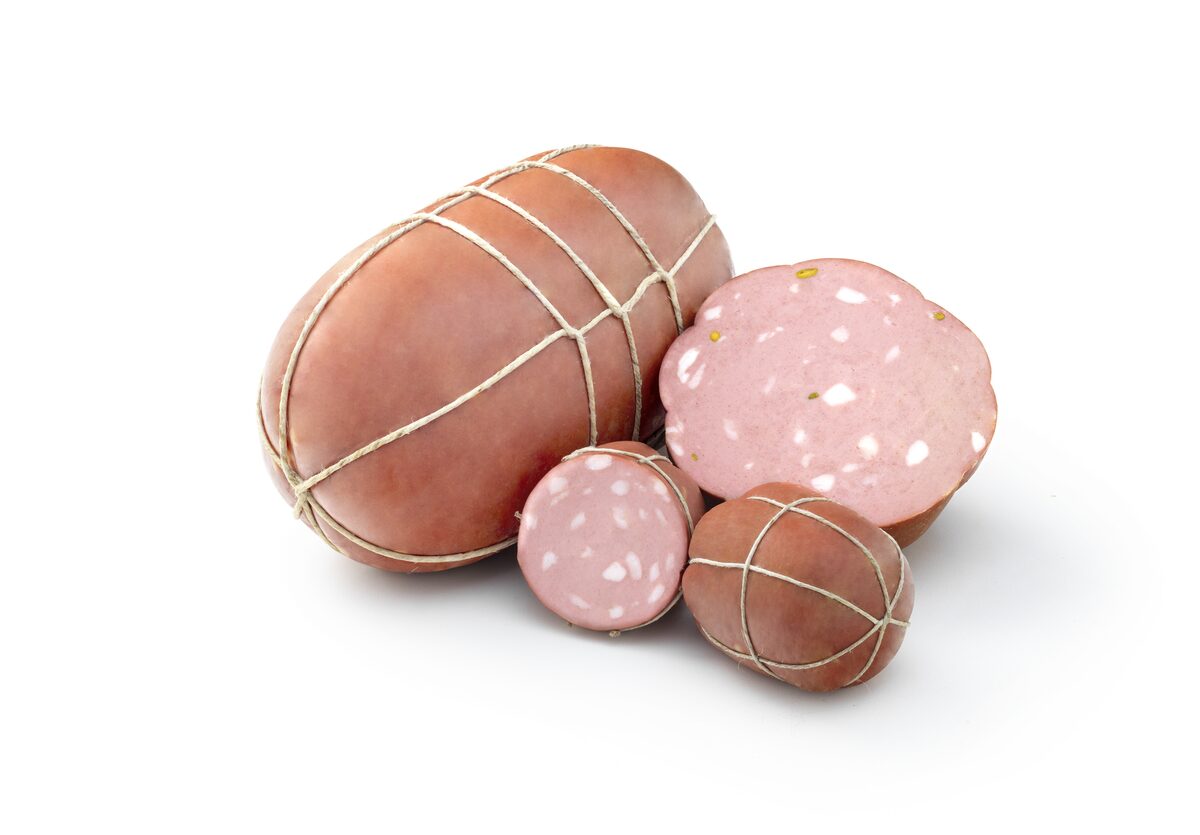 A whole mortadella tied with string, next to slices showing the pale fat cubes