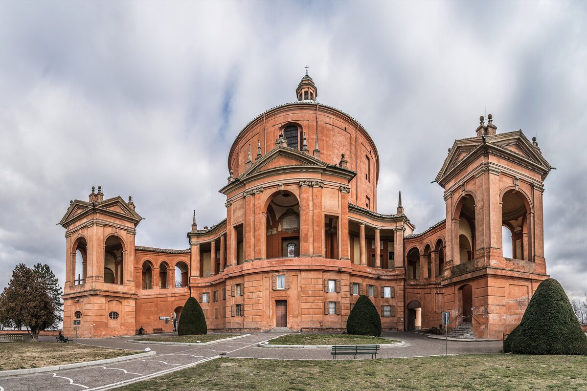 The domed brick sanctuary of San Luca on its hill, with two side towers under a cloudy sky