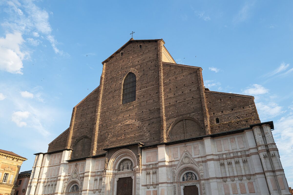 The brick facade of San Petronio under a blue sky, with its pale marble lower section