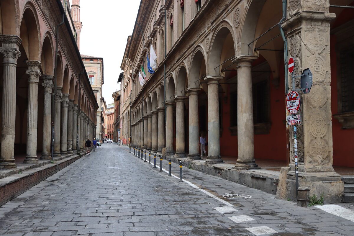 A long street lined by the stone columns and arches of a portico