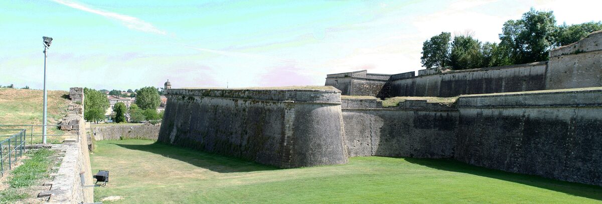 The massive stone ramparts and bastion of the Blaye citadel with a grass moat in front
