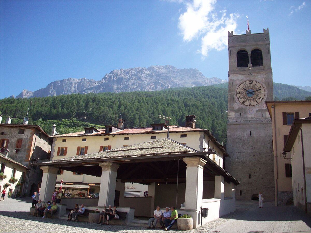 The open arcade of the Kuerc in Piazza Cavour, with the clock tower of the Torre della Bajona behind it